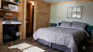 Ein Schlafzimmer mit einem Bett, einer kleinen Küchenzeile und einer Holzwand.