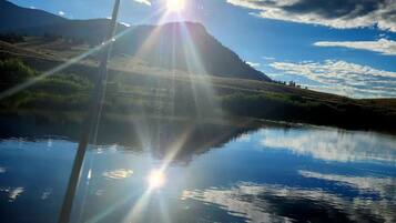 Un paysage de montagne avec un ciel dégagé et une étendue d’eau qui reflète le soleil.