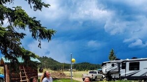 Eine Gruppe von Menschen spielt draußen in der Nähe einer Holzhütte und Wohnmobilen.