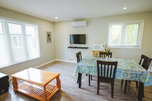 A dining area with a table covered in a patterned tablecloth, surrounded by chairs. - Pelican Cottage - 2-Bedroom Cottage – Family Friendly (Trent Lakes)