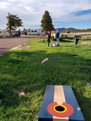A grassy area with a target-like object, a trailer, and a vehicle in the background.