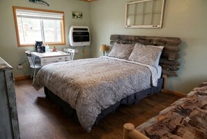 A bedroom with a bed, a desk, a chair, a lamp, and a window. - Cabin#9 in Lake George Cabins & RV Park (Lake George)