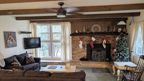 A cozy living room with a fireplace, a television, and a Christmas tree. - Family-Friendly and Pet Friendly Pine Cabin - Elk Views on the Deck (Pine)