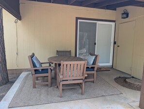 An outdoor patio with a wooden table and chairs, a textured rug, and a sliding glass door. - Family-Friendly and Pet Friendly Pine Cabin - Elk Views on the Deck (Pine)