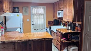 Una cucina compatta con mobili in legno, un'isola centrale, un forno a microonde e un frigorifero.