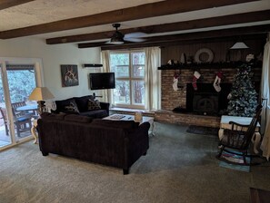 A cozy living room with a fireplace, a television, and a Christmas tree. - Family-Friendly and Pet Friendly Pine Cabin - Elk Views on the Deck (Pine)