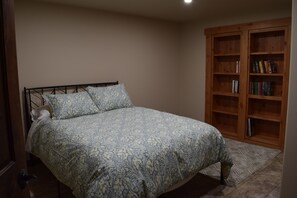 Quarto com cama, guarda-roupa de madeira e colcha estampada.