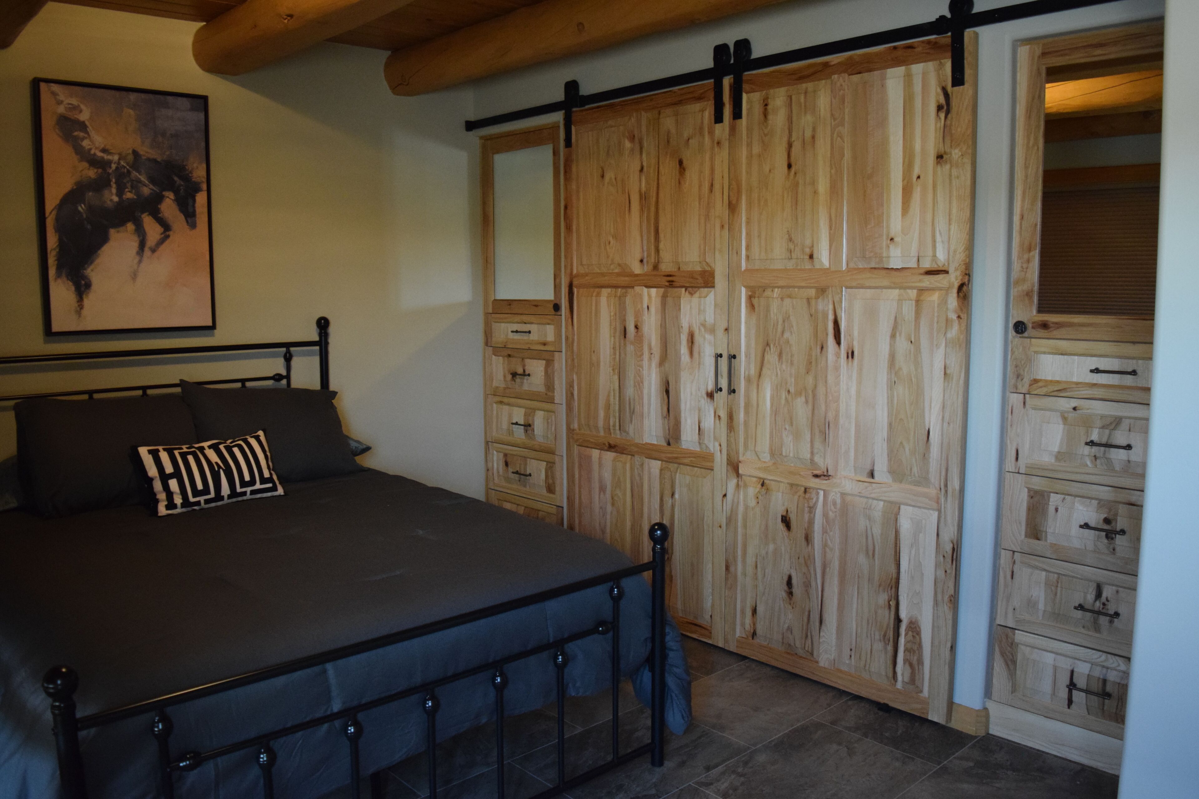 A bedroom with a bed, a wooden wardrobe, and a painting on the wall.