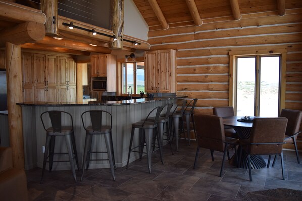 A log cabin interior with a bar area, dining space, and large windows.