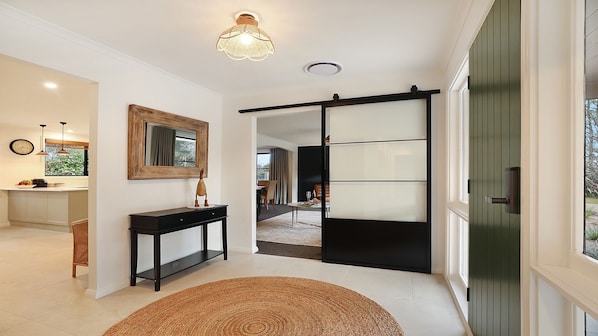 A modern interior with a sliding door, a console table, and a dining area in the background.