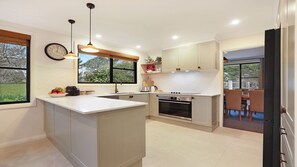 A modern kitchen with a central island, built-in oven, and pendant lighting.
