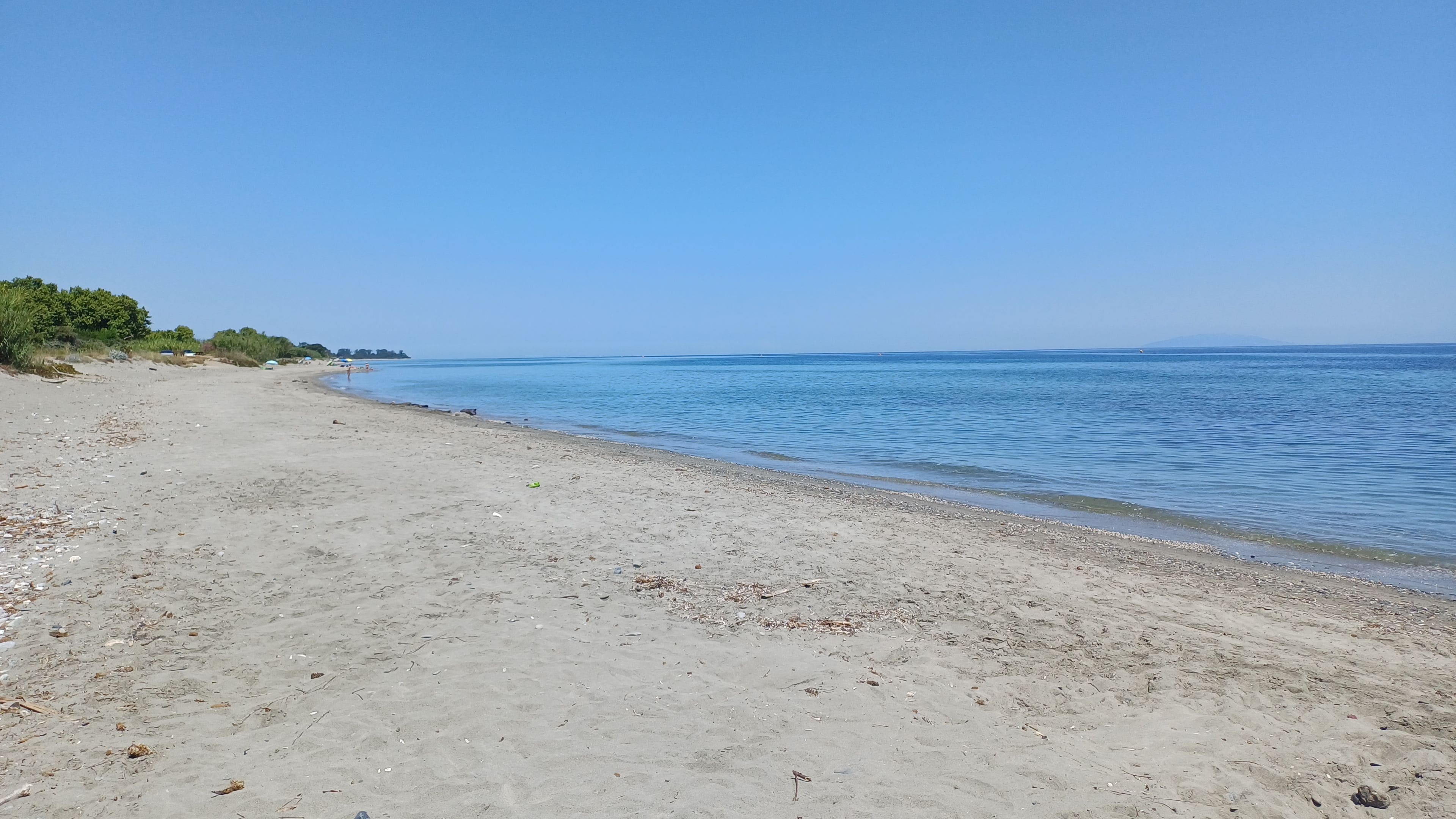 A sandy beach with calm water and a clear sky.