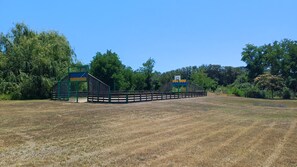 Ein von Zäunen umgebener Außenbereich mit Spielplatz und Basketballfeld.