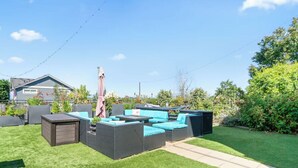 Un patio trasero con un sofá modular, una mesita y una sombrilla.