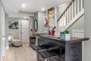 A kitchen with a bar area, a staircase, and a dining area with two chairs.