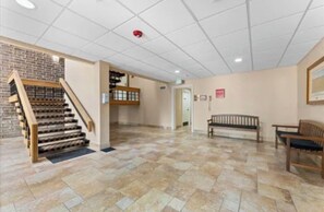 A spacious lobby with a wooden staircase, a bench, and a tiled floor. - Dream Condo in Palm Harbor, Fl ~ 2Bed/2Bath (Palm Harbor)