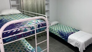 A dormitory room with bunk beds, a small shelf unit, and a curtain. - Welcome to our app, "Unexpected" (onverwacht)