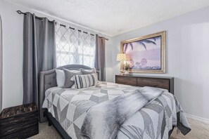 Ein Schlafzimmer mit einem Bett, einem Nachttisch, einer Lampe und einem Bild an der Wand.