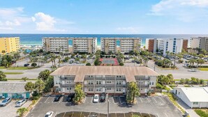A multi-story hotel with a parking lot, a tennis court, and a view of the ocean. - Coastal Getaway on Okaloosa Island - 3 Minute Walk to Beach! (Fort Walton Beach)