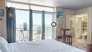 Ein Hotelzimmer mit einem großen Bett, einem Balkon mit Aussicht und einem durchgegangenen Tür sichtbaren Badezimmer.