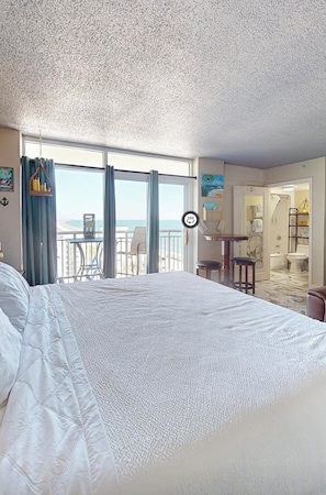 A hotel room with a large bed, a balcony with a view, and a bathroom visible through an open door. - Perfect Couples Retreat in North Myrtle (North Myrtle Beach)