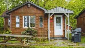 Eine Holzhütte mit Veranda, Grill und Picknicktisch.