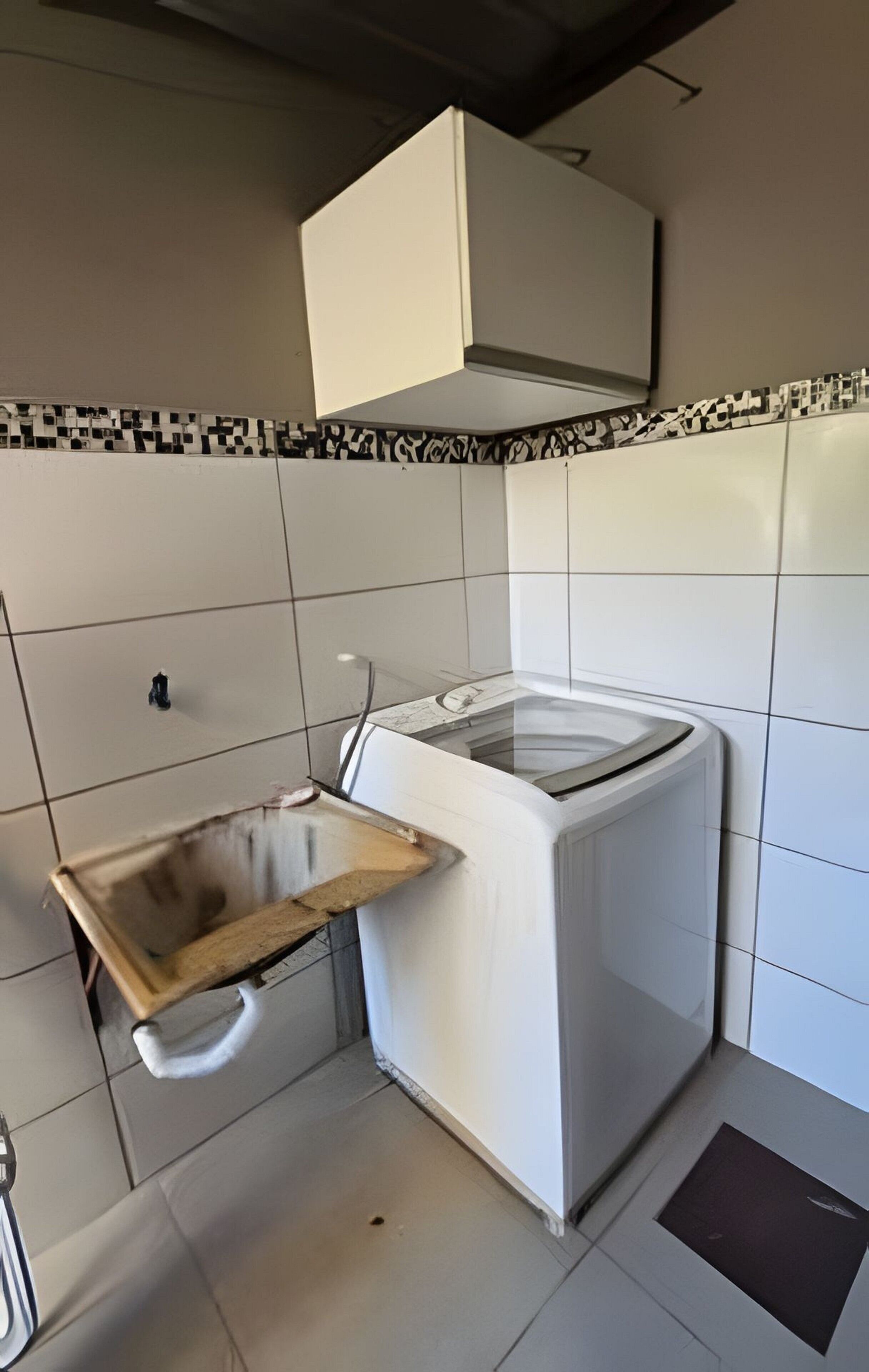 A compact laundry area with a washing machine, a drying rack, and a tiled backsplash.