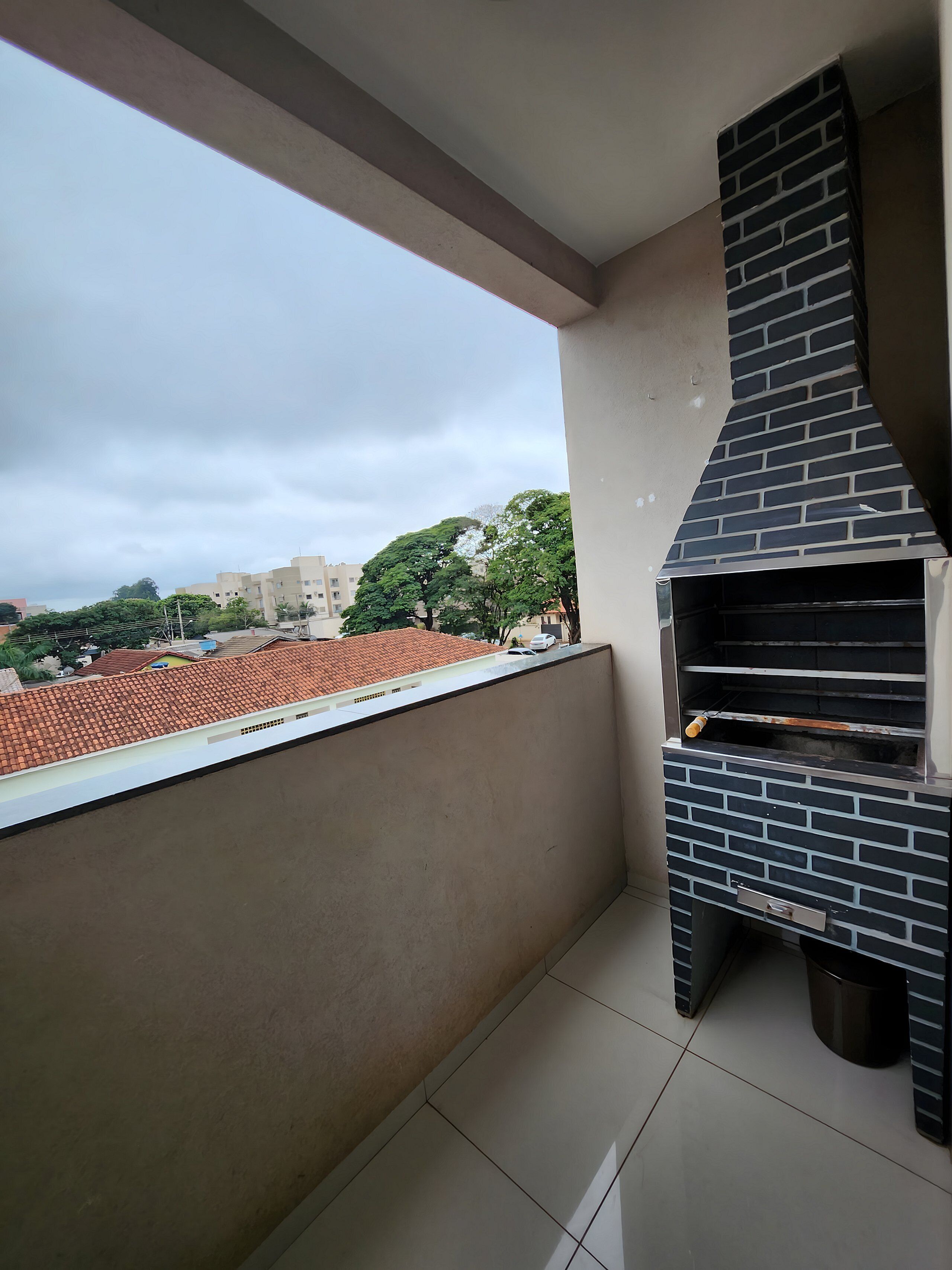 A balcony with a brick oven and a view of a cityscape.
