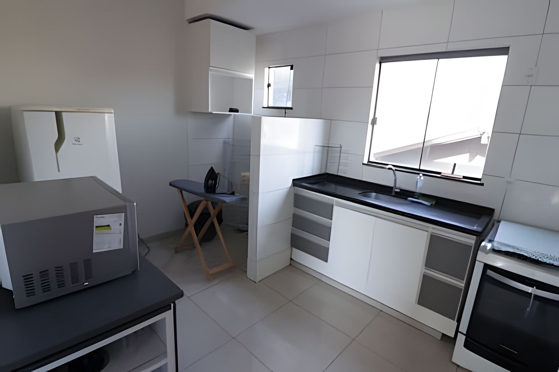 Una cocina moderna con armarios blancos, encimera negra y ventana que proporciona luz natural.