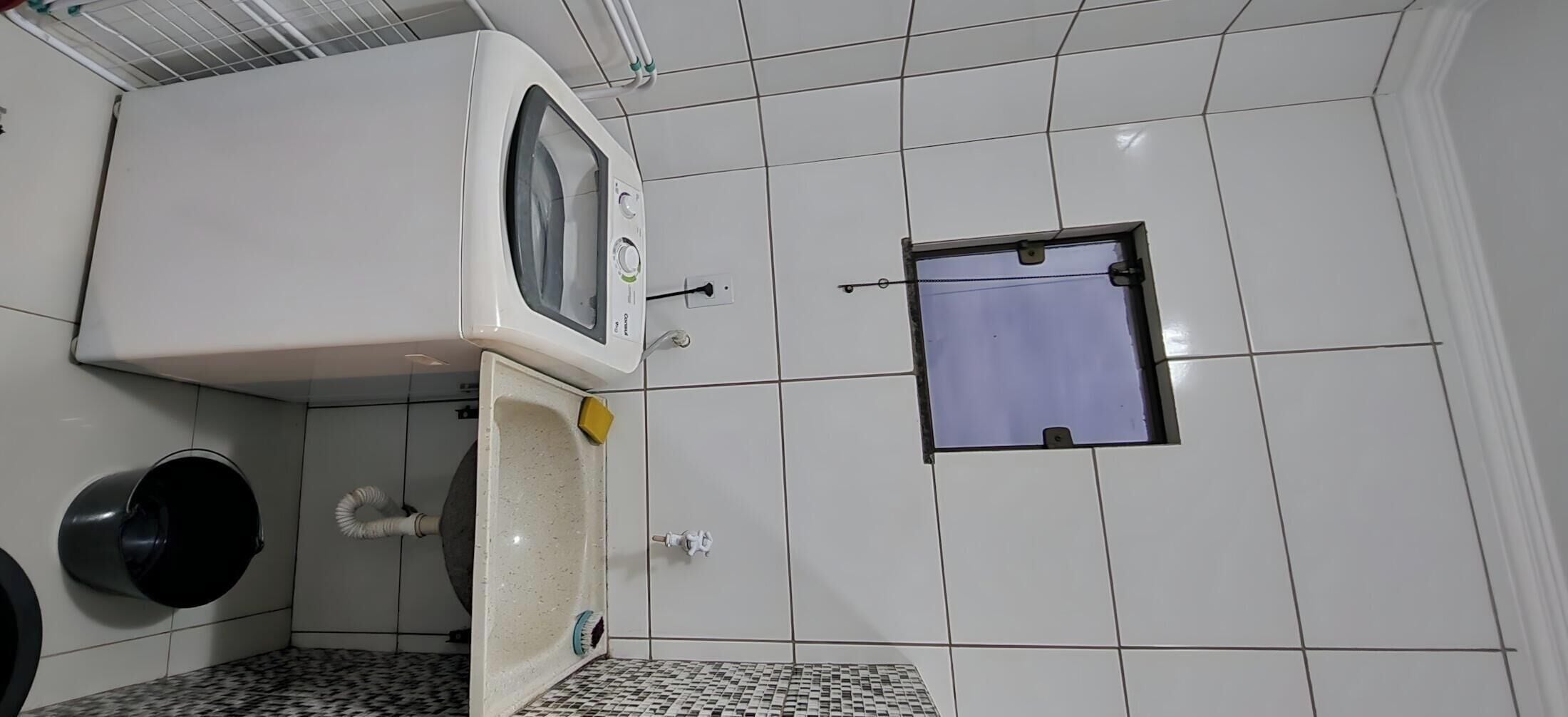 Et badeværelse med flisegulv, et håndvask, et spejl, et toilet og et vindue.