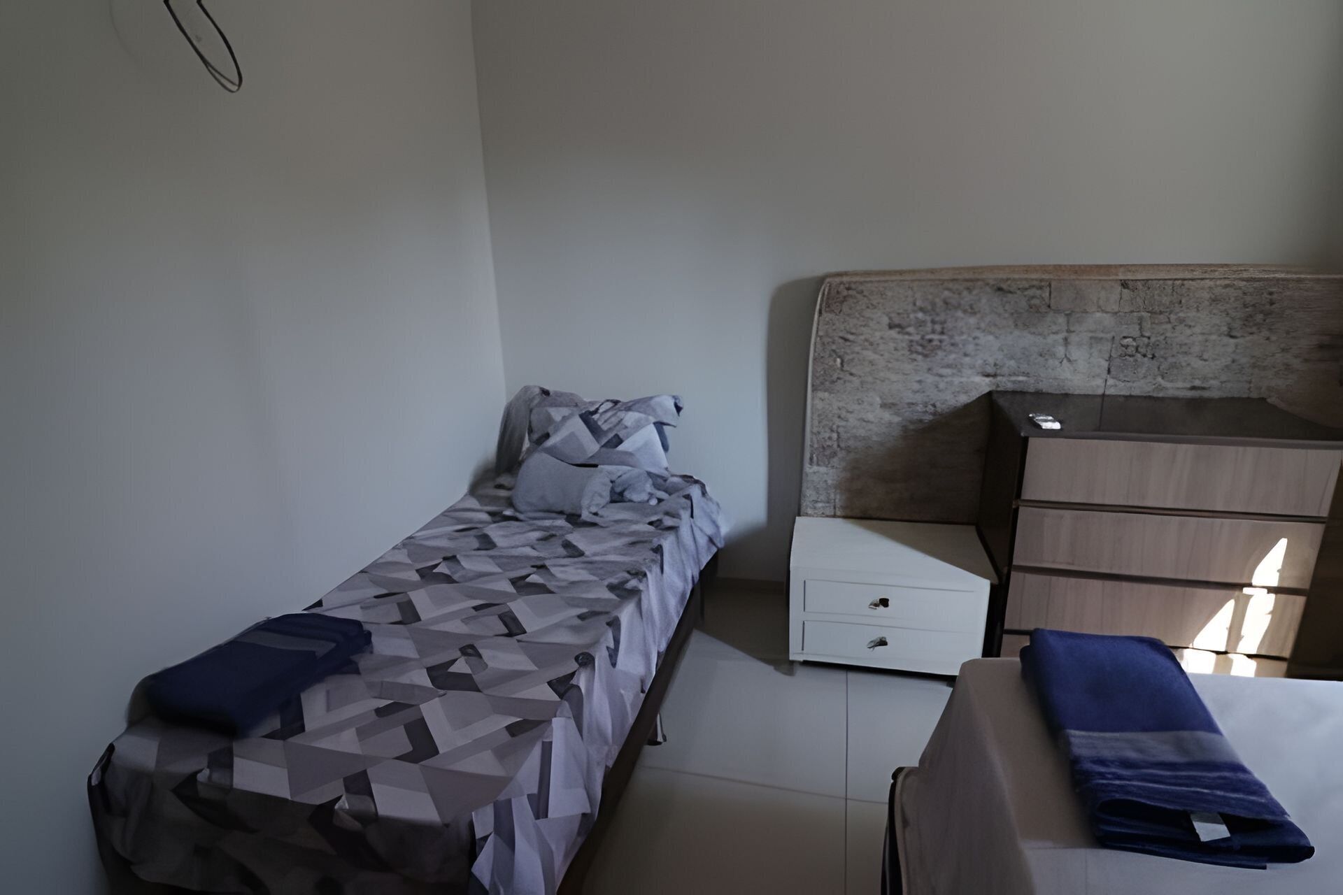 Quarto com cama, cômoda e mesa de cabeceira.