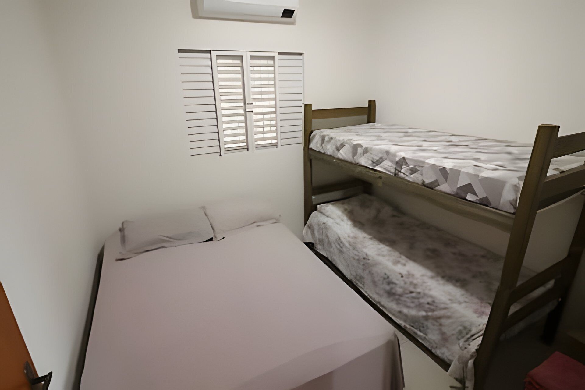 A small, single-bed room with a bunk bed and a window with blinds.