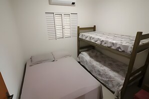 Una habitación pequeña con una cama individual, literas y una ventana con persianas.