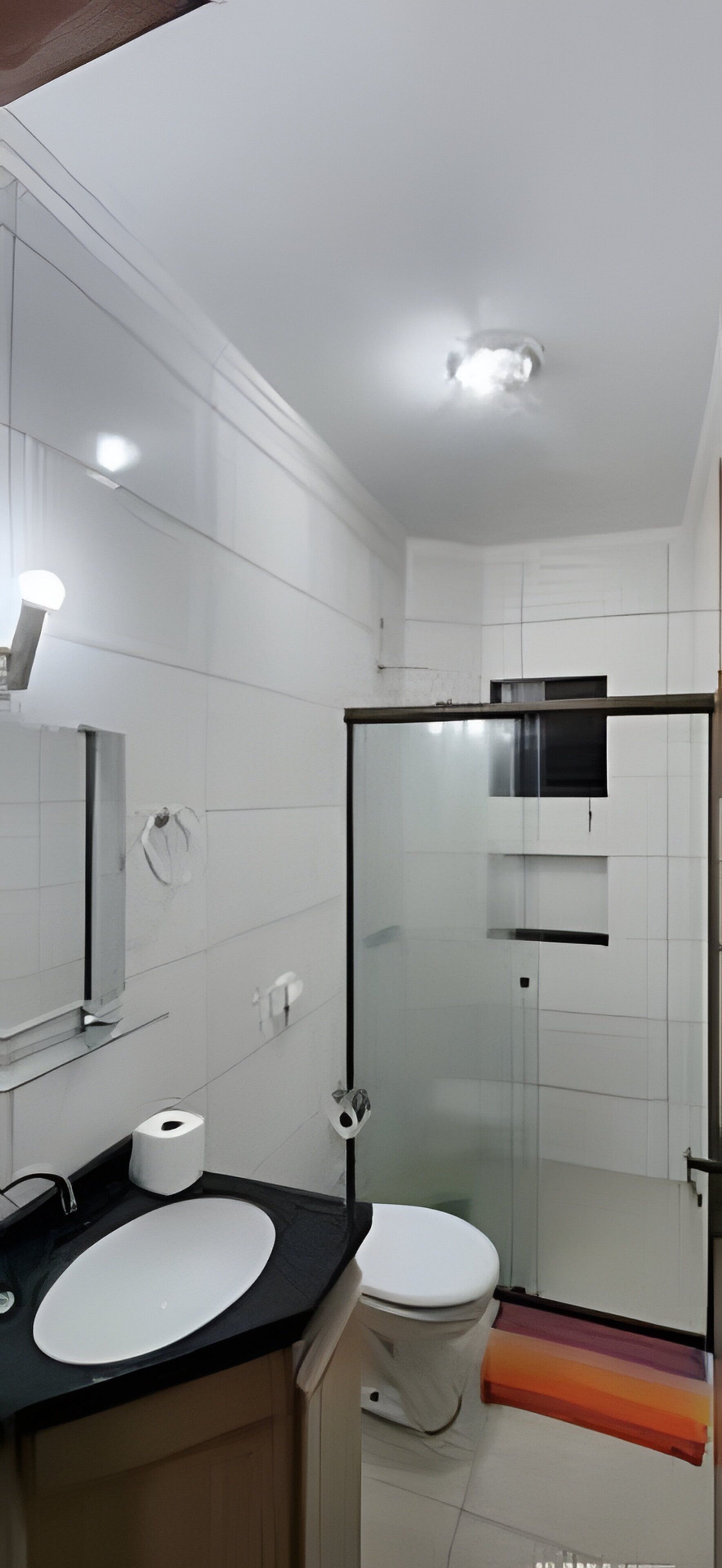 A modern bathroom with a white sink, toilet, and glass shower enclosure.