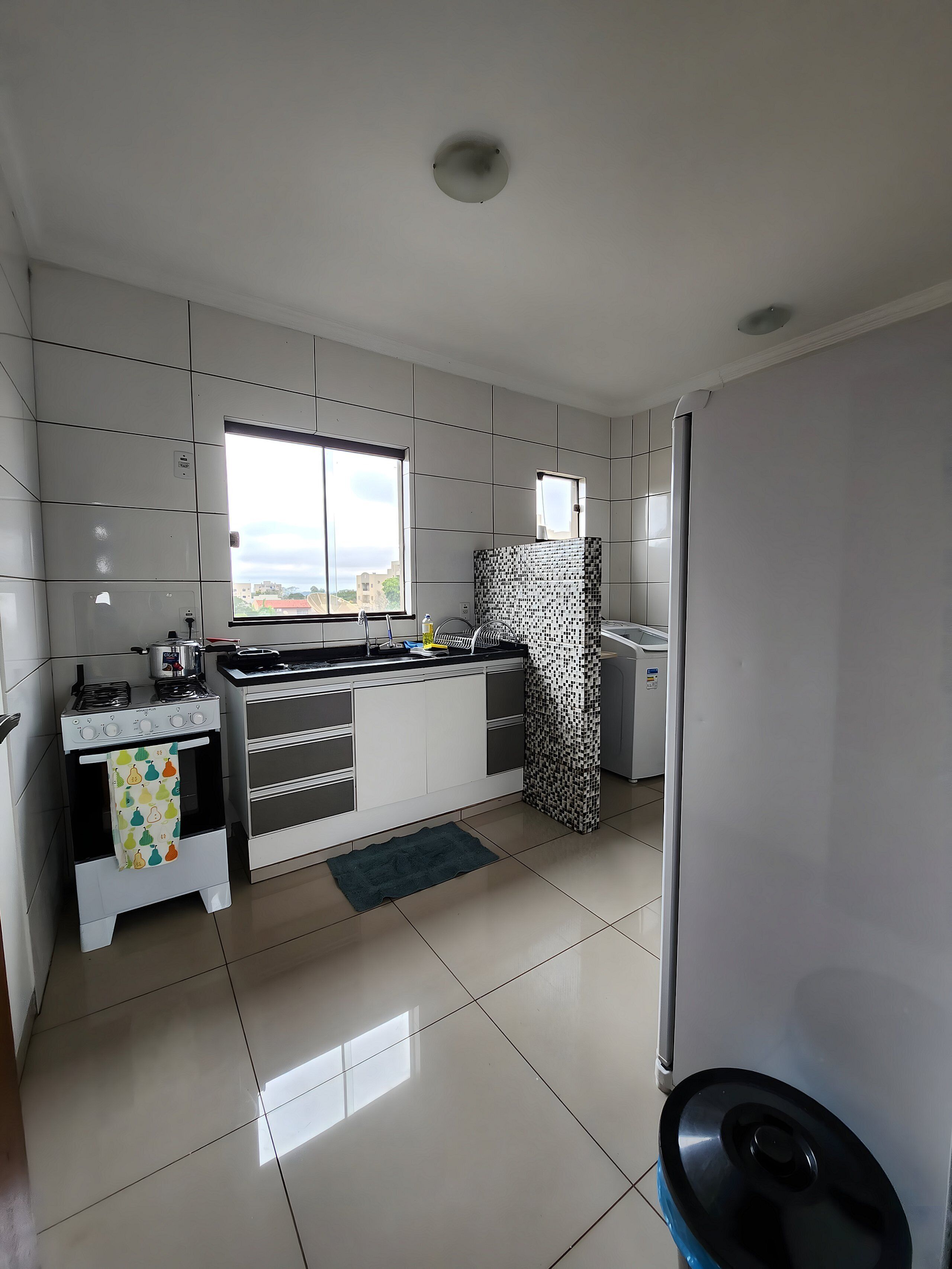 Una cocina moderna con armarios blancos, estufa, refrigerador y ventana.