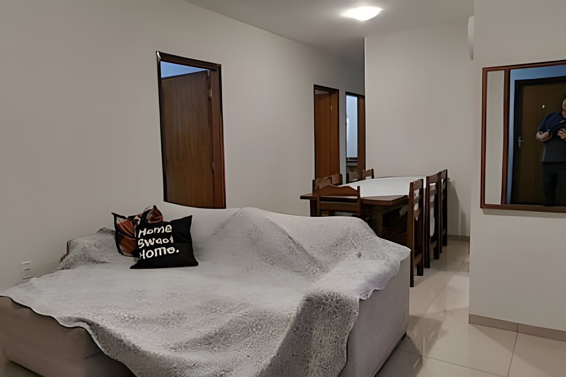 Una sala de estar con un sofá, una mesa de comedor con sillas y un ventanal grande.