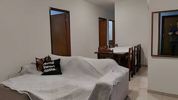 Una sala de estar con un sofá, una mesa de comedor con sillas y un ventanal grande.