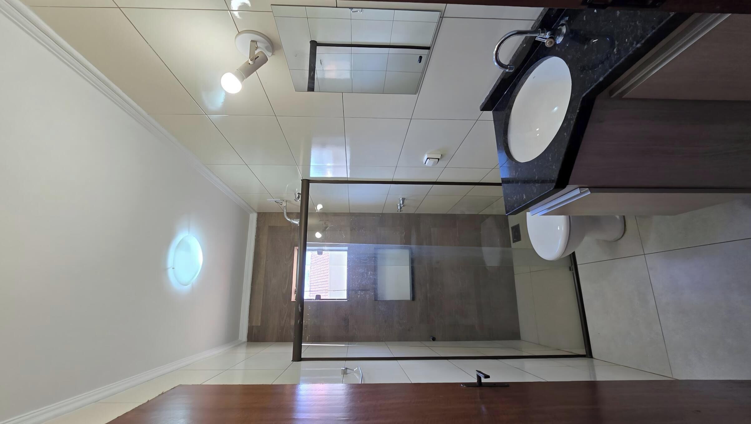 A modern bathroom with a large mirror, two sinks, and a shower area.
