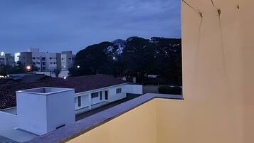 Um bairro residencial com um edifício de telhado plano, uma parede externa branca e uma rua arborizada ao entardecer.