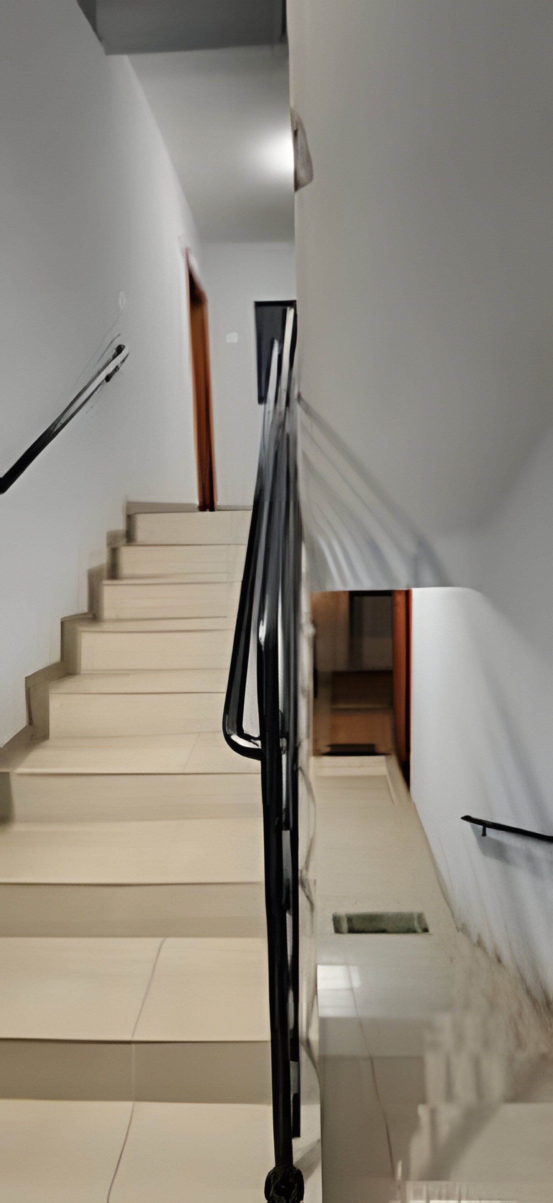 A staircase with a handrail, leading to a landing with a door.