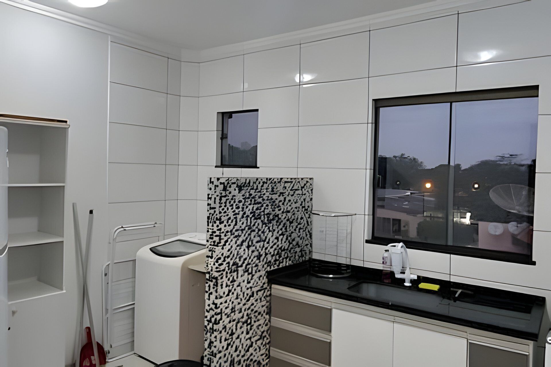 Una cocina moderna con armarios blancos, encimera negra y ventana con vistas a la ciudad.