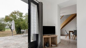 A modern living room with a television on a wooden stand, a small table, and a staircase leading to an upper level.