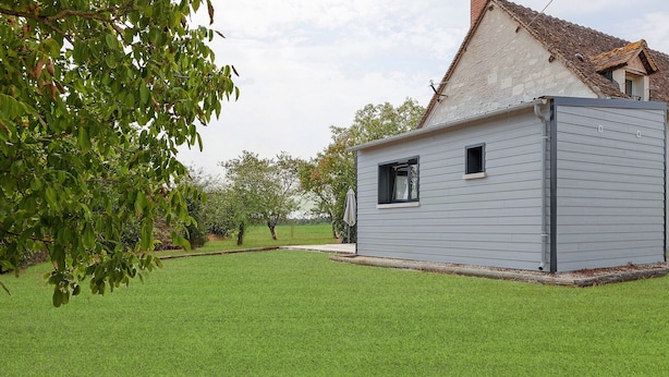 A small, single-story building with a sloped roof, surrounded by a well-maintained lawn.