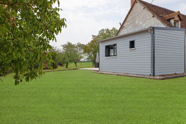 A small, single-story building with a sloped roof, surrounded by a well-maintained lawn.