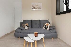 A modern living room with a grey sofa, a white coffee table, and a framed artwork on the wall.