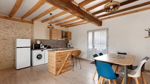 Eine moderne Küche mit Holzbalken, einer eingebauten Waschmaschine und einem Essbereich mit blauen Stühlen.