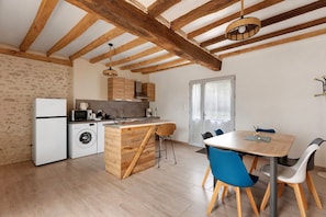 Een moderne keuken met houten balken, een ingebouwde wasmachine en een eethoek met blauwe stoelen.