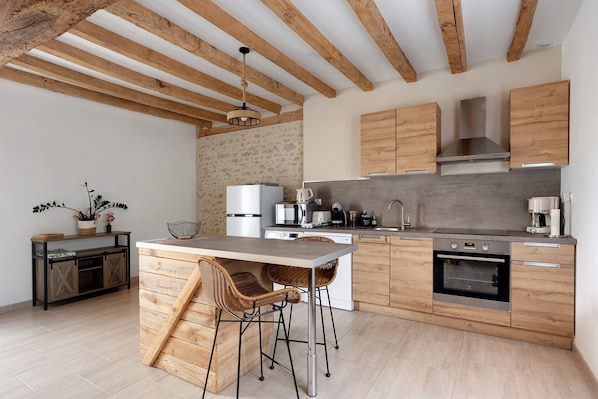 A modern kitchen with wooden beams, a central island with bar stools, and built-in appliances.