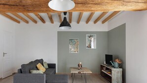Ein modernes Wohnzimmer mit grauem Sofa, einem Holztisch und einem Fernseher auf einem rustikalen Schrank.