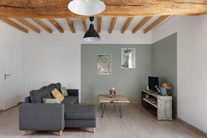 Een moderne woonkamer met een grijze bank, een houten salontafel en een televisie op een rustieke dressoir.